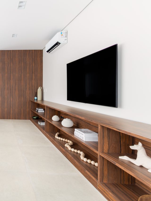 Marcenaria em pau-ferro percorre apartamento criando continuidade visual. Projeto de ResiliArt Arquitetura.