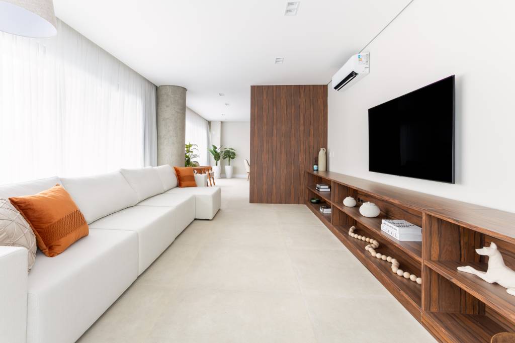 Marcenaria em pau-ferro percorre apartamento criando continuidade visual. Projeto de ResiliArt Arquitetura.