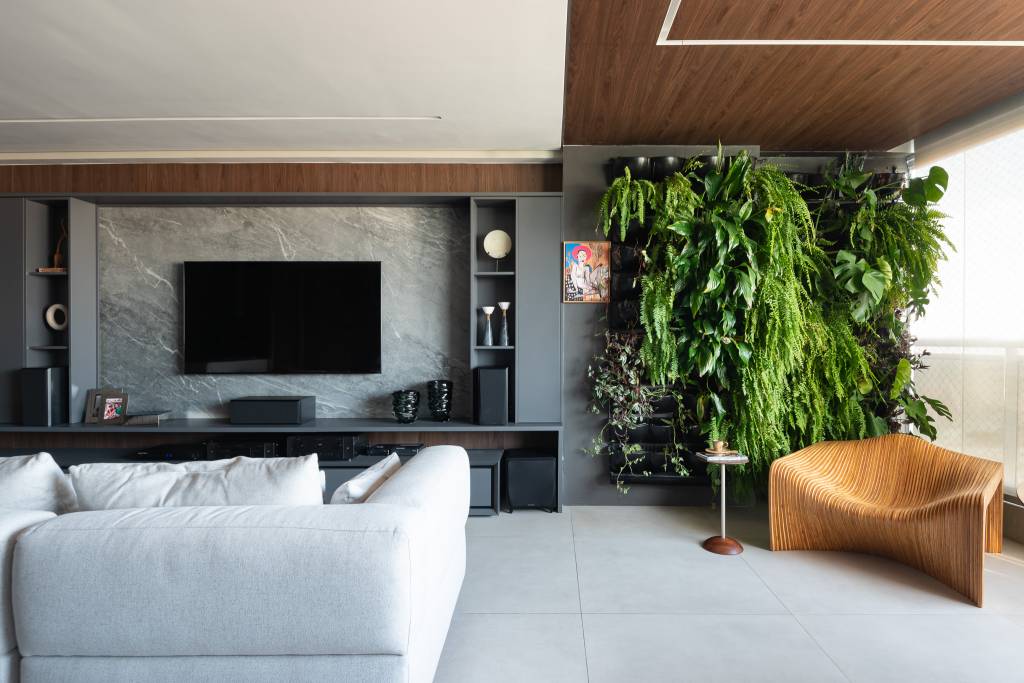 Sala de vinhos elegante tem estante personalizada, poltronas de couro e uma vitrola. Projeto de Grace Dantas Arquitetura.