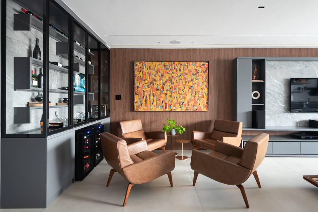 Sala de vinhos elegante tem estante personalizada, poltronas de couro e uma vitrola