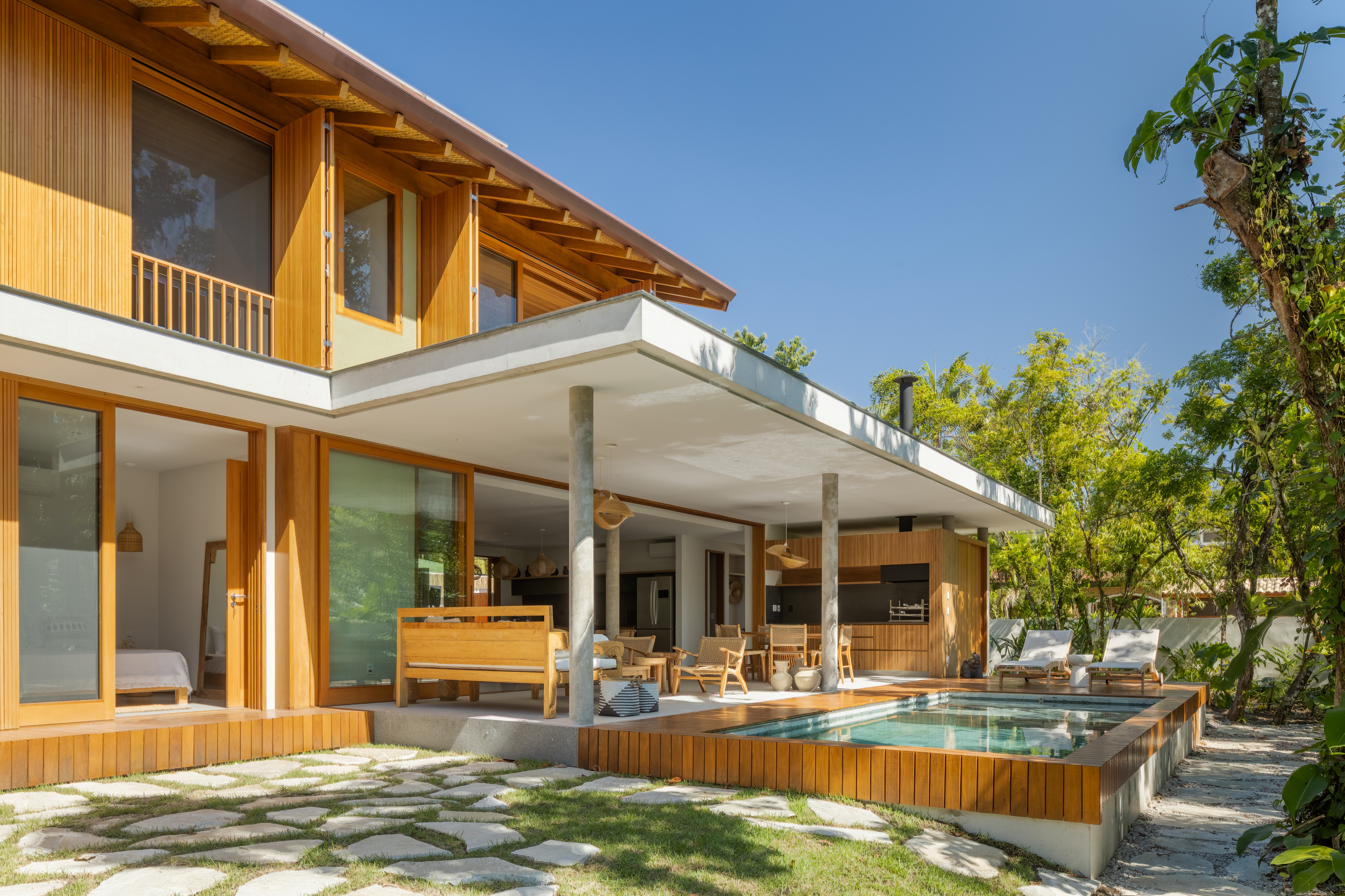 Linda casa com em Ubatuba tem materiais leves e janela-banco entre cozinha e jantar. Projeto de Pitta Arquitetura.