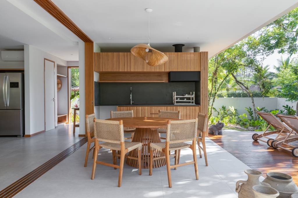 Linda casa com em Ubatuba tem materiais leves e janela-banco entre cozinha e jantar. Projeto de Pitta Arquitetura.