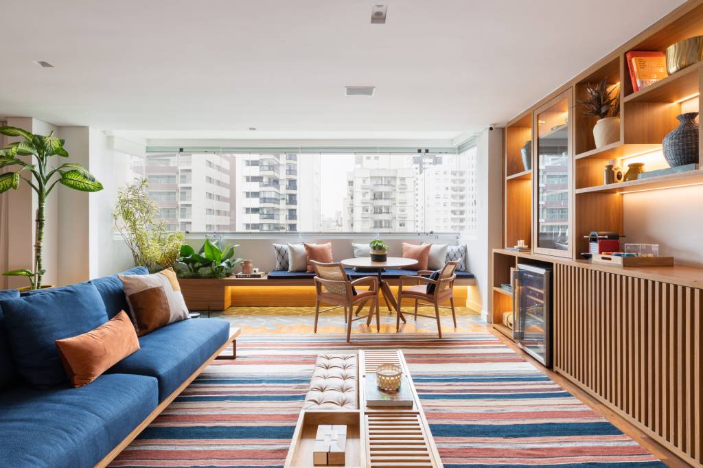 Ladrilhos e tacos se misturam na varanda integrada deste apê com banco e jardineira