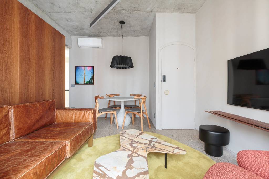 Marcenaria de madeira sucupira é destaque em apartamento compacto com vibe industrial. Projeto de Pro.a Arquitetos.