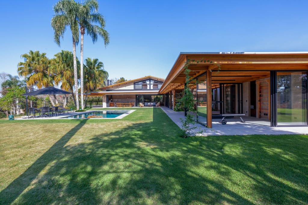 Suíte principal, academia e sauna são interligadas por pergolado nesta casa de campo. Projeto de Sandra Sayeg.