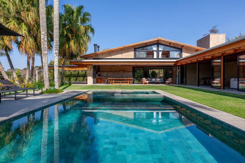 Suíte principal, academia e sauna são interligadas por pergolado nesta casa de campo