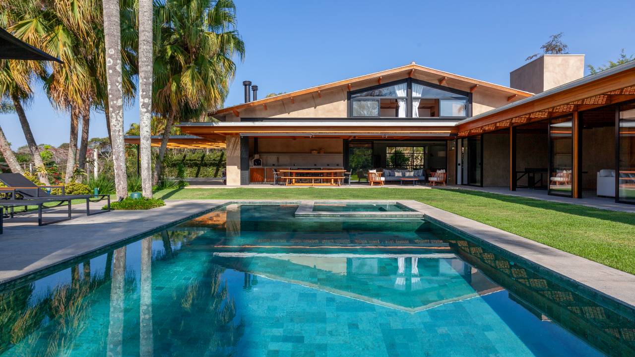 Suíte principal, academia e sauna são interligadas por pergolado nesta casa de campo. Projeto de Sandra Sayeg.