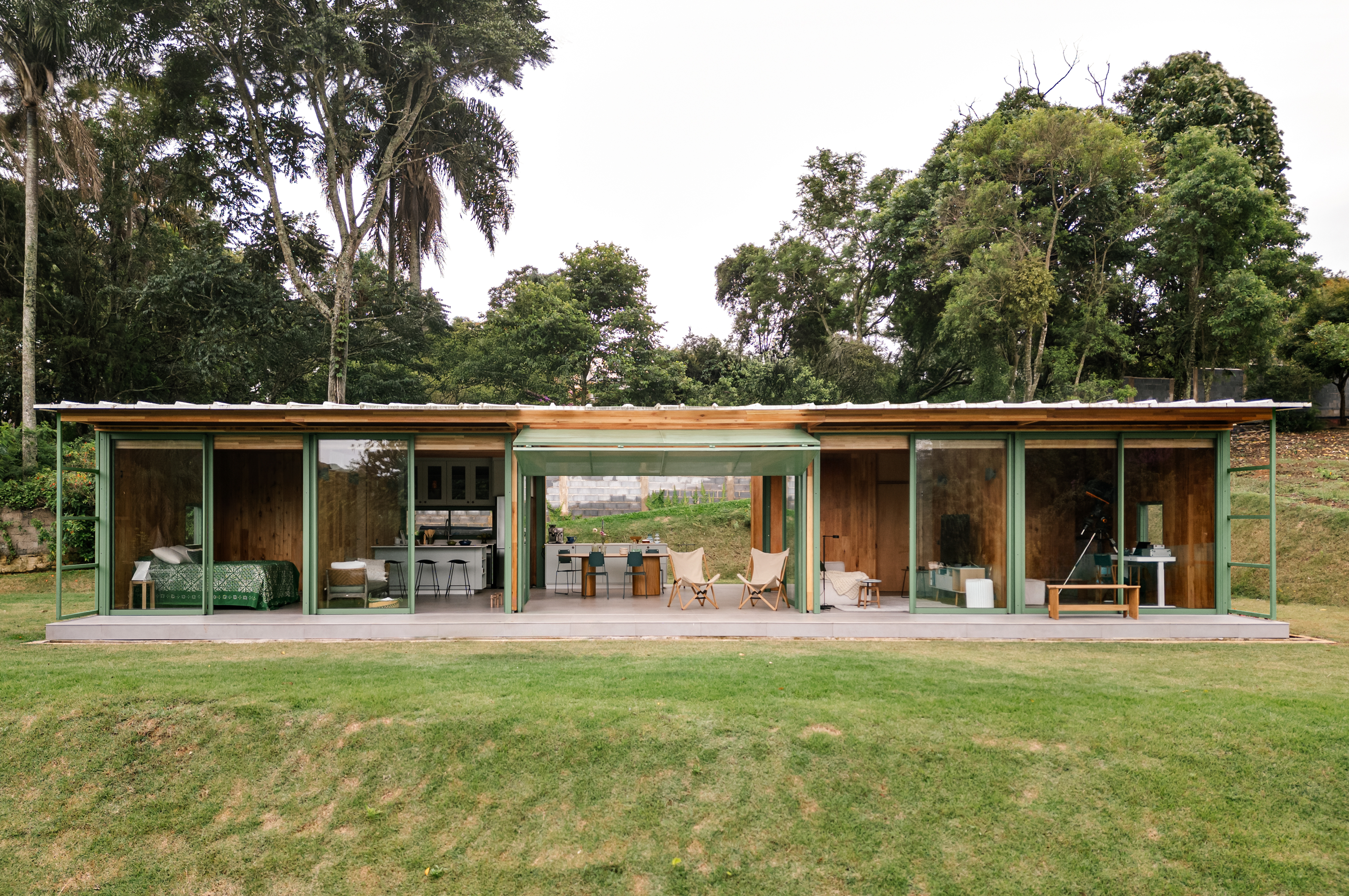 Varanda com telhas transparentes fica entre blocos de casa em CLT montada em 1 semana. Projeto de Nitsche Arquitetos.