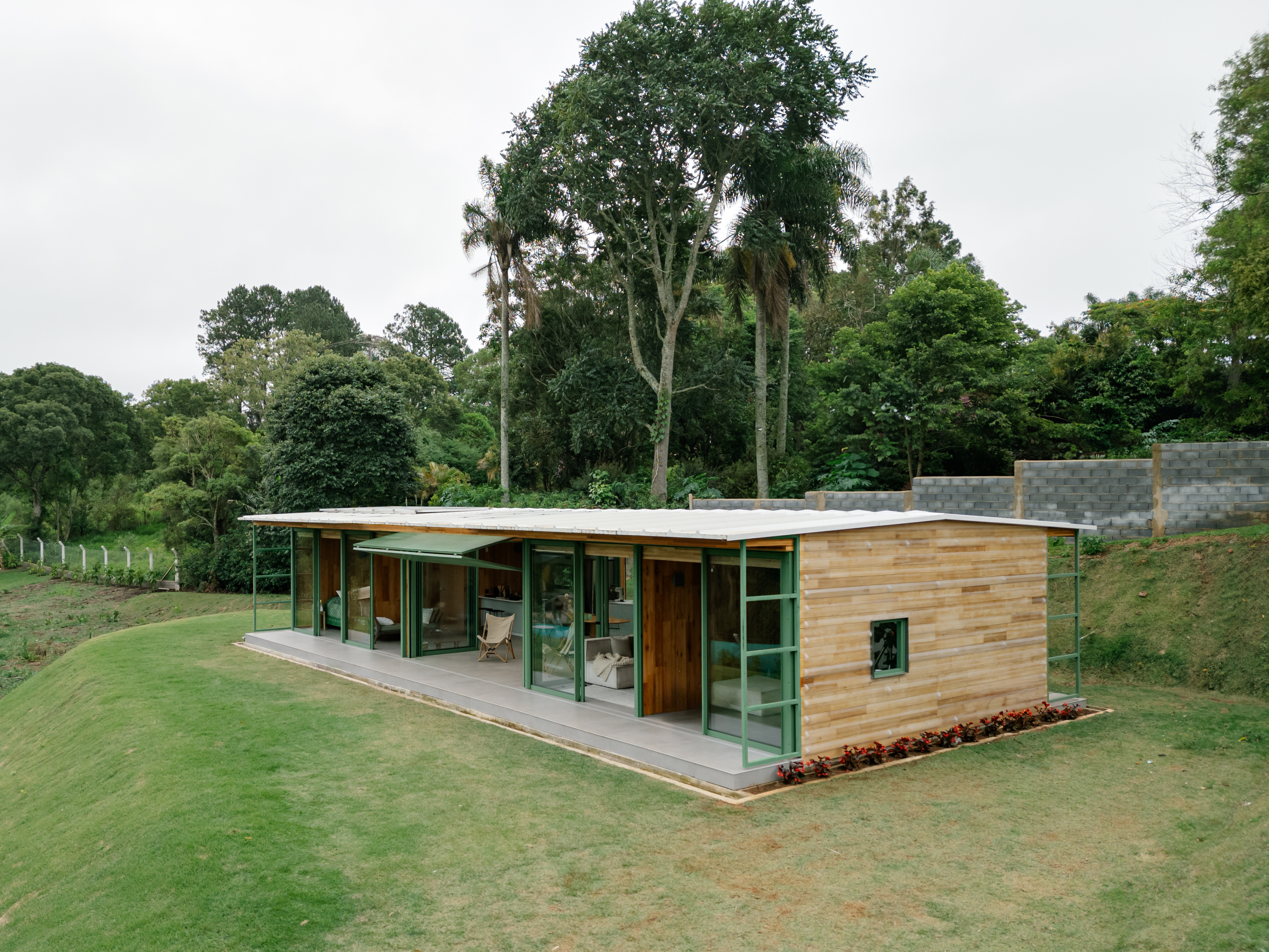 Varanda com telhas transparentes fica entre blocos de casa em CLT montada em 1 semana. Projeto de Nitsche Arquitetos.