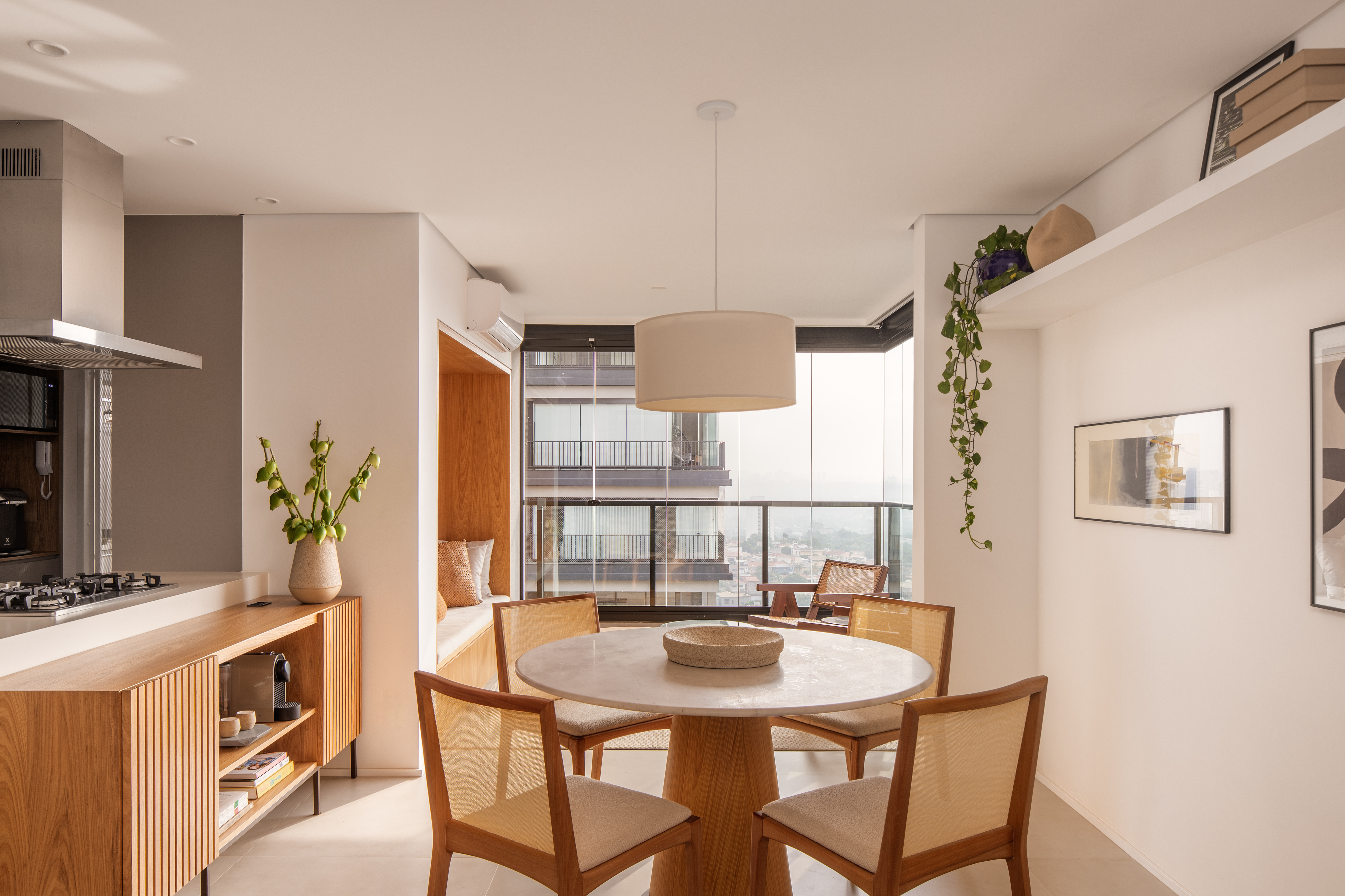 Apê ganha sofá pequeno embutido na marcenaria para contemplar vista. Projeto de W. Arquitetura.
