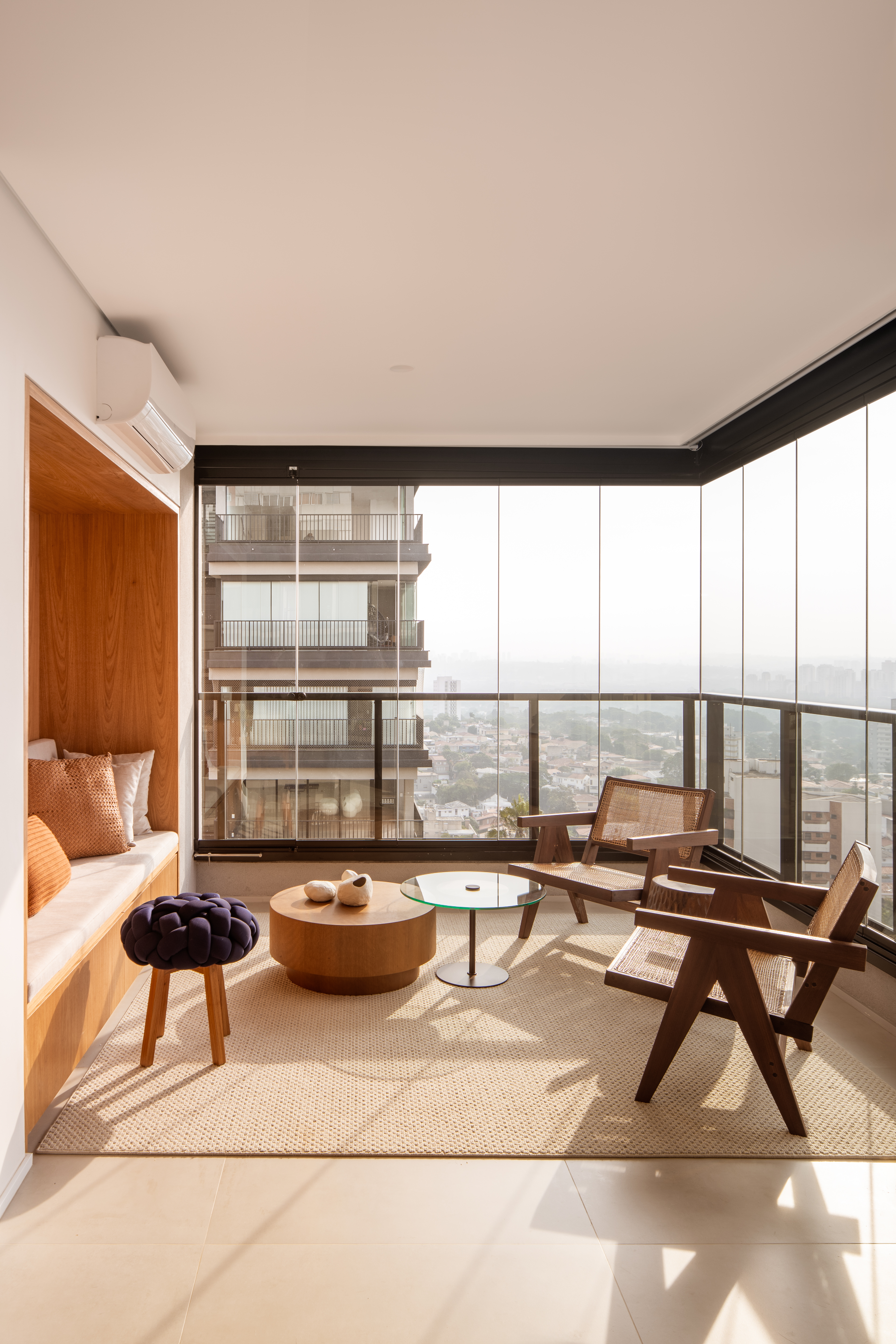 Apê ganha sofá pequeno embutido na marcenaria para contemplar vista. Projeto de W. Arquitetura.