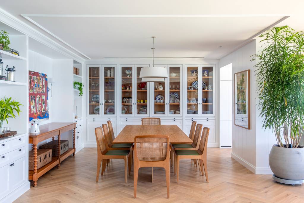Cristaleira piso-teto dá charme a sala de jantar deste apê de frente para o mar
