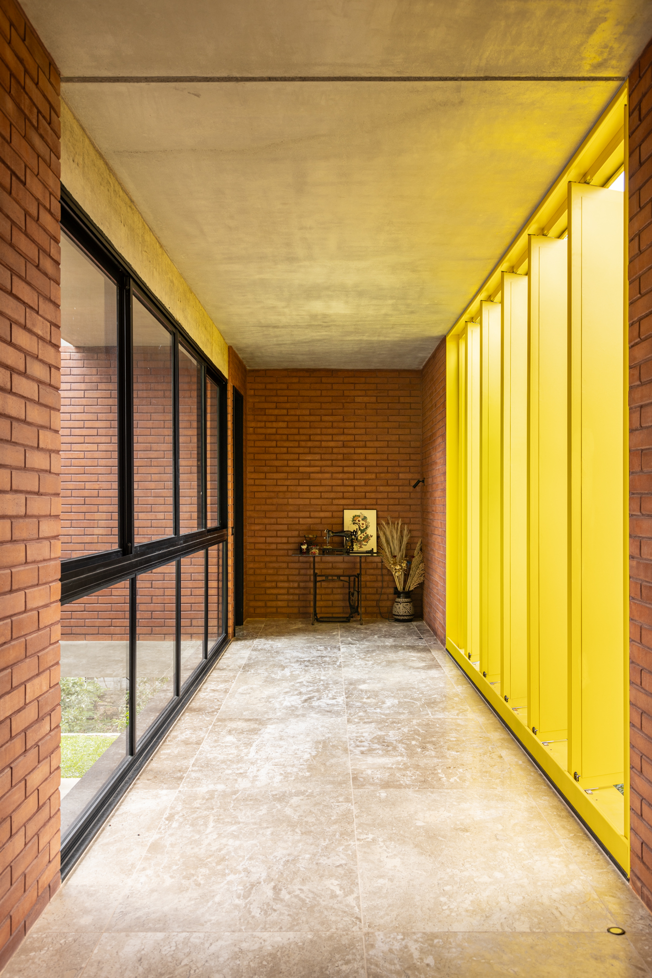 Passarela com brises metálicos amarelos conectam áreas desta casa no mato. Projeto de Hersen Mendes Arquitetura.