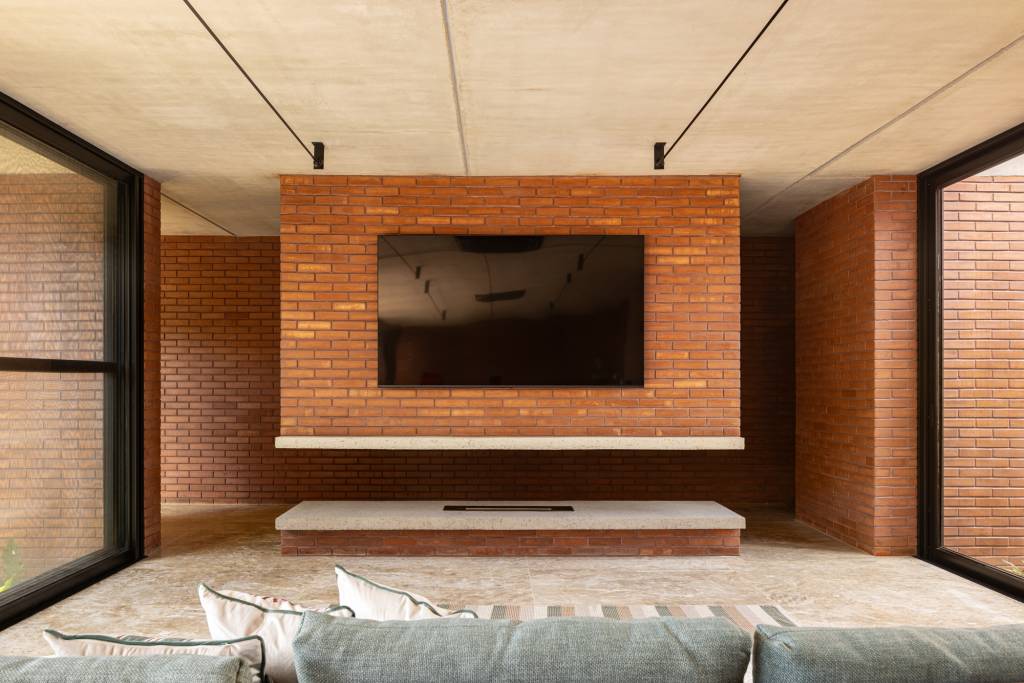 Passarela com brises metálicos amarelos conectam áreas desta casa no mato. Projeto de Hersen Mendes Arquitetura.