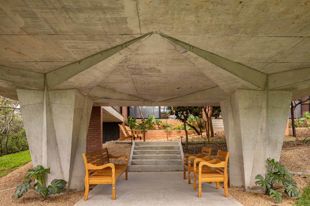 Passarela com brises metálicos amarelos conectam áreas desta casa no mato. Projeto de Hersen Mendes Arquitetura.