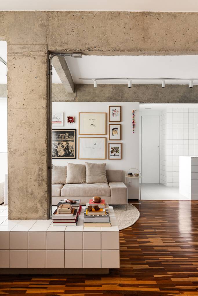 Apê tem piso de tacos reciclados e azulejos brancos pequenos na cozinha. Projeto de BLOCO Arquitetos.