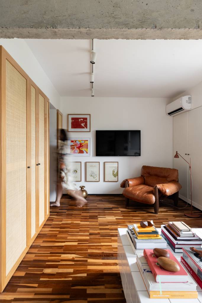 Apê tem piso de tacos reciclados e azulejos brancos pequenos na cozinha. Projeto de BLOCO Arquitetos.