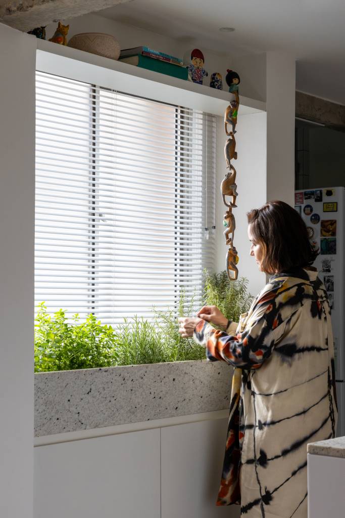 Apê tem piso de tacos reciclados e azulejos brancos pequenos na cozinha. Projeto de BLOCO Arquitetos.