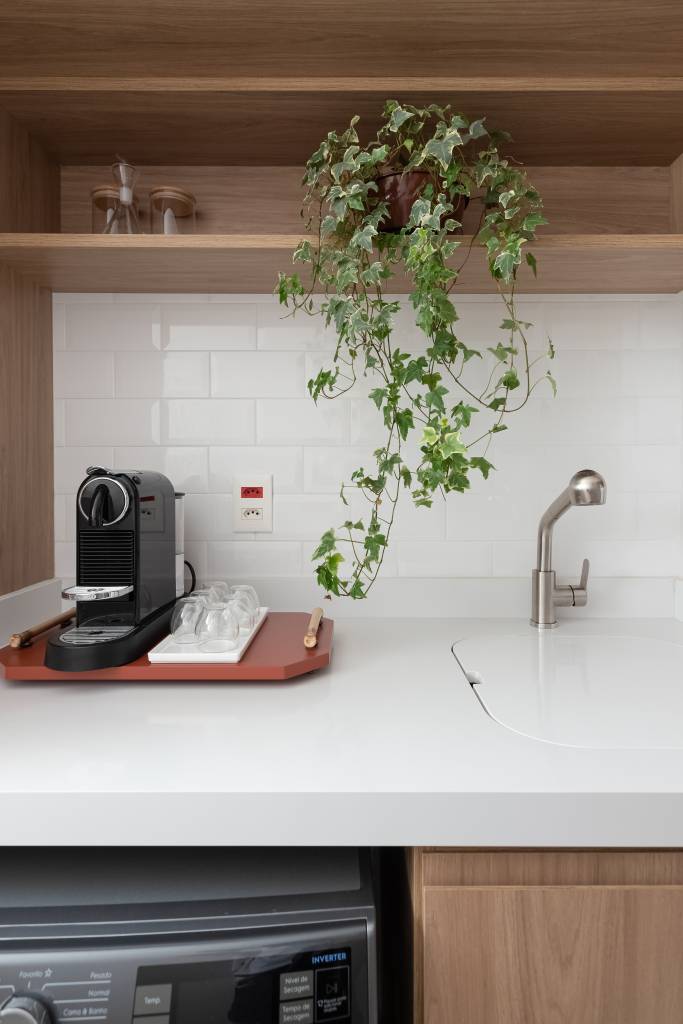 Móvel antigo funciona como bar e apoio para a mesa de jantar em apê de 69 m². Projeto de Studio Monfré. Na foto, bancada de cozinha, backsplash de subway tiles, cantinho do café, planta suspensa.