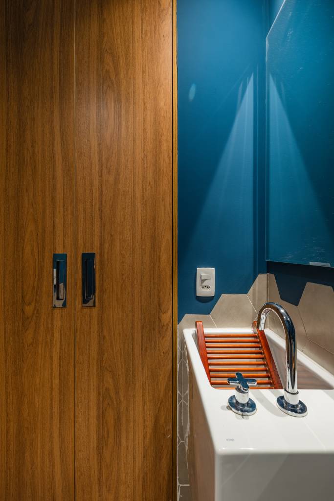 Estúdio tem mesa para seis pessoas, duas áreas de estar e lavanderia no lavabo. Projeto de STAL Arquitetura.