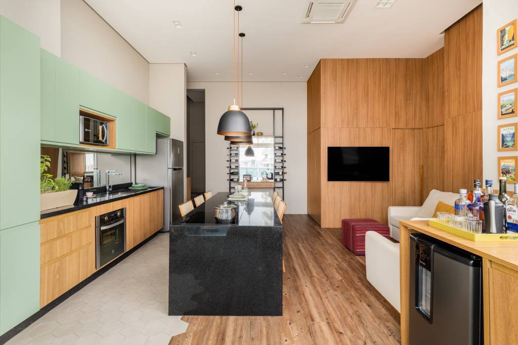 Estúdio tem mesa para seis pessoas, duas áreas de estar e lavanderia no lavabo. Projeto de STAL Arquitetura.