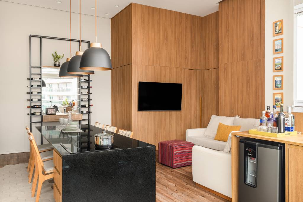 Estúdio tem mesa para seis pessoas, duas áreas de estar e lavanderia no lavabo. Projeto de STAL Arquitetura.