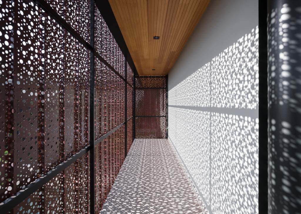 Painel metálico perfurado cria jogos de luz e sombra em casa de 450 m²