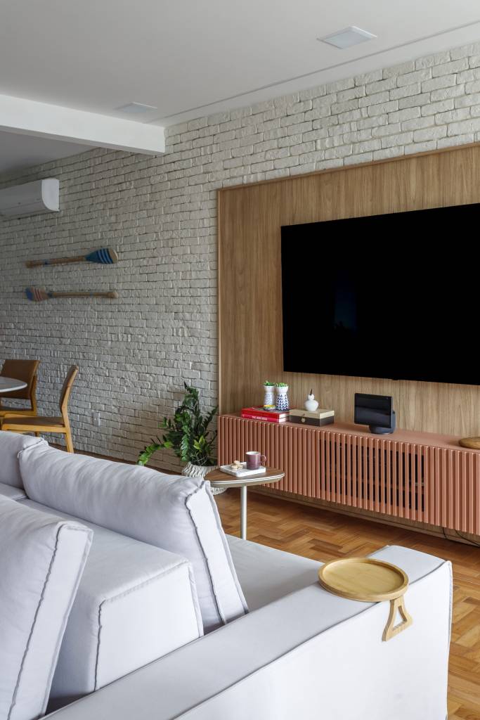 Apartamento tem parede de tijolinhos e MDF azul petróleo na cozinha. Projeto de Vita Arquitetura.