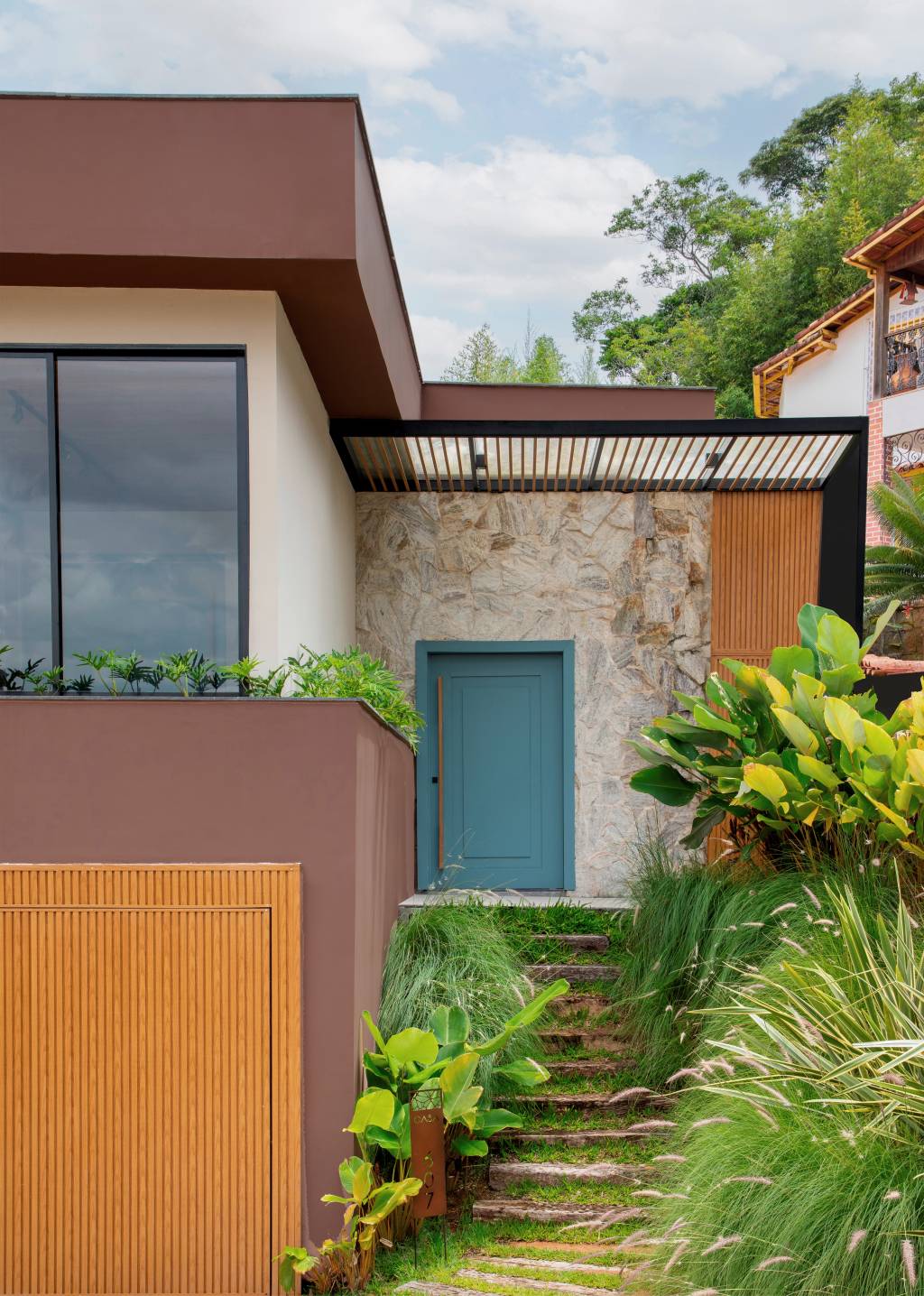 Jardineiras com Filodendros contornam as esquadrias desta casa no mato