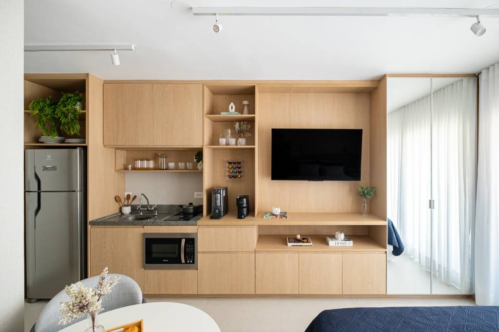 Miniapartamento de 24 m² tem sofá-cama e cozinha linear completa. Projeto de VilaVille Arquitetura.