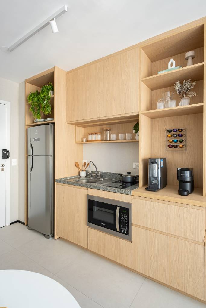 Miniapartamento de 24 m² tem sofá-cama e cozinha linear completa. Projeto de VilaVille Arquitetura.