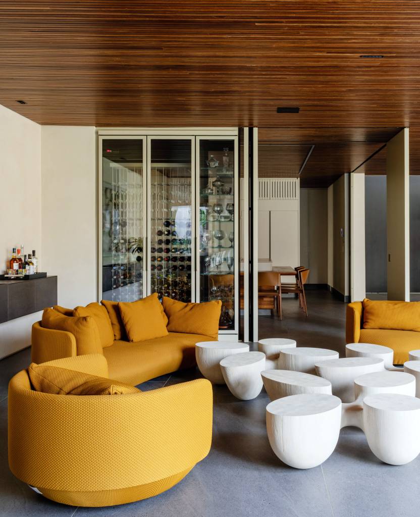 Casa de 880m² em São Paulo se integra ao jardim após ampla reforma. Projeto de Studio DWG. Living com adega ao fundo.