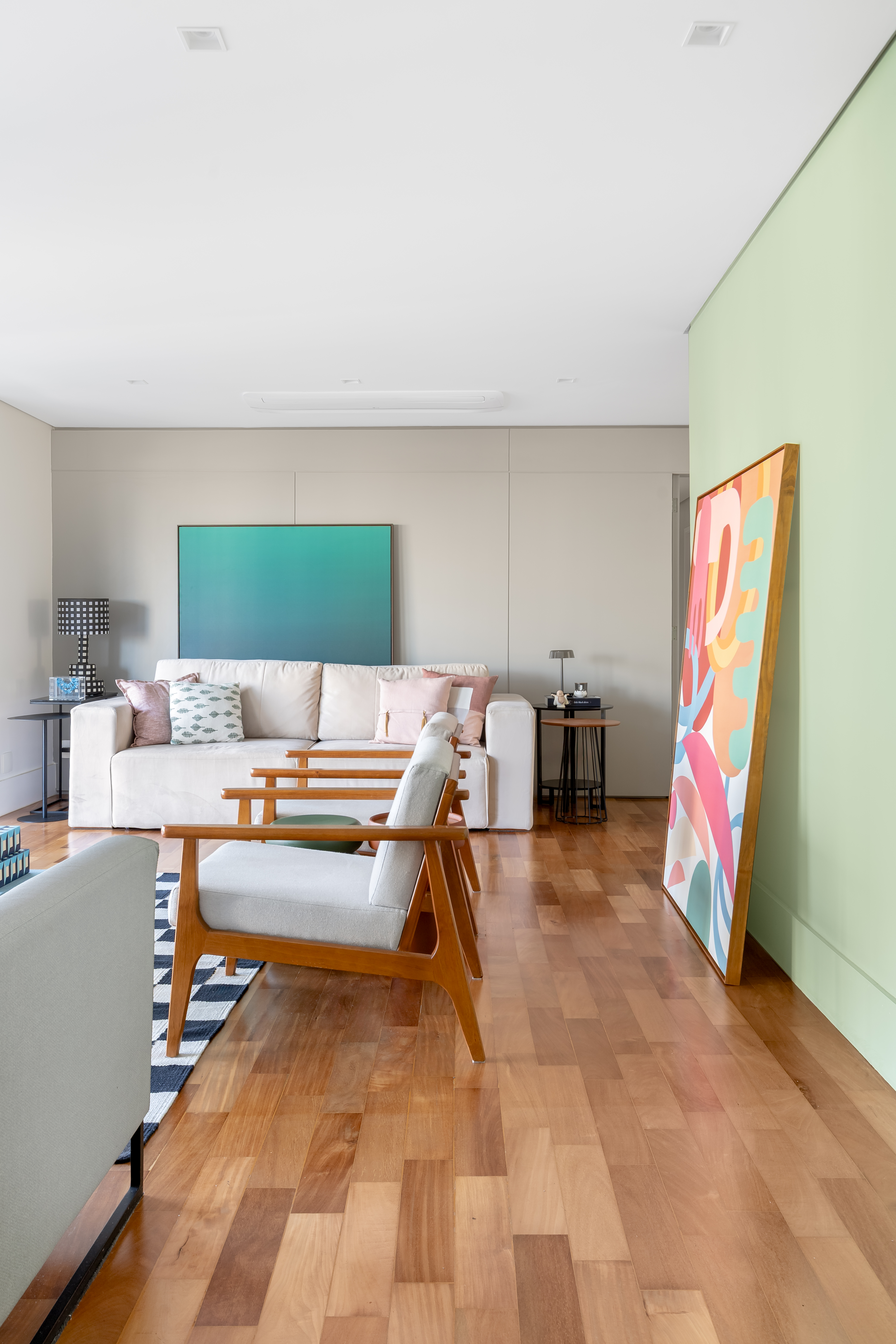 Reforma de apê usa piso e marcenaria originais para destacar revestimentos e pontos de cor. Projeto de Raquel Neves. Living integrado com jantar e parede verde.