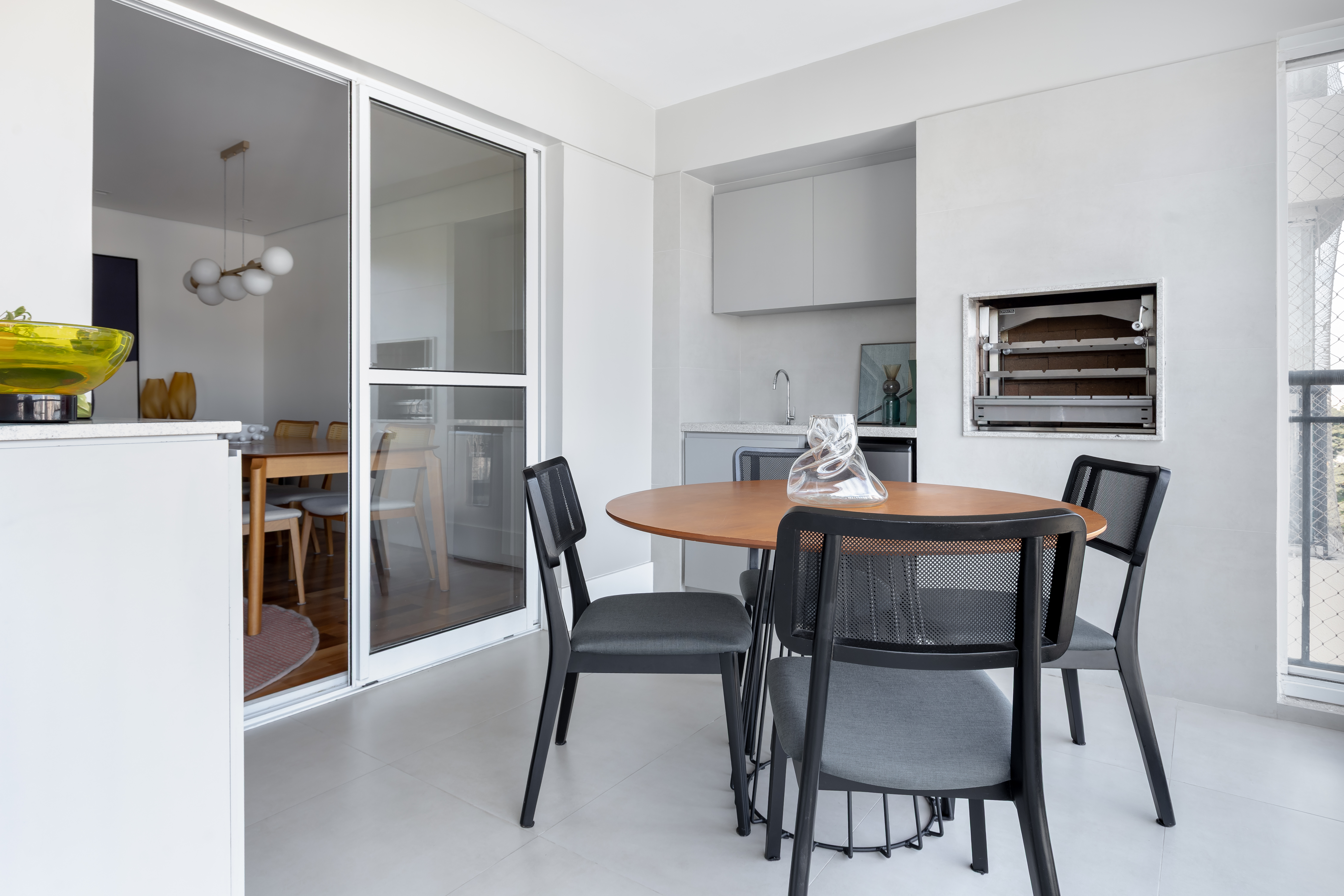 Reforma de apê usa piso e marcenaria originais para destacar revestimentos e pontos de cor. Projeto de Raquel Neves. Varanda com churrasqueira.