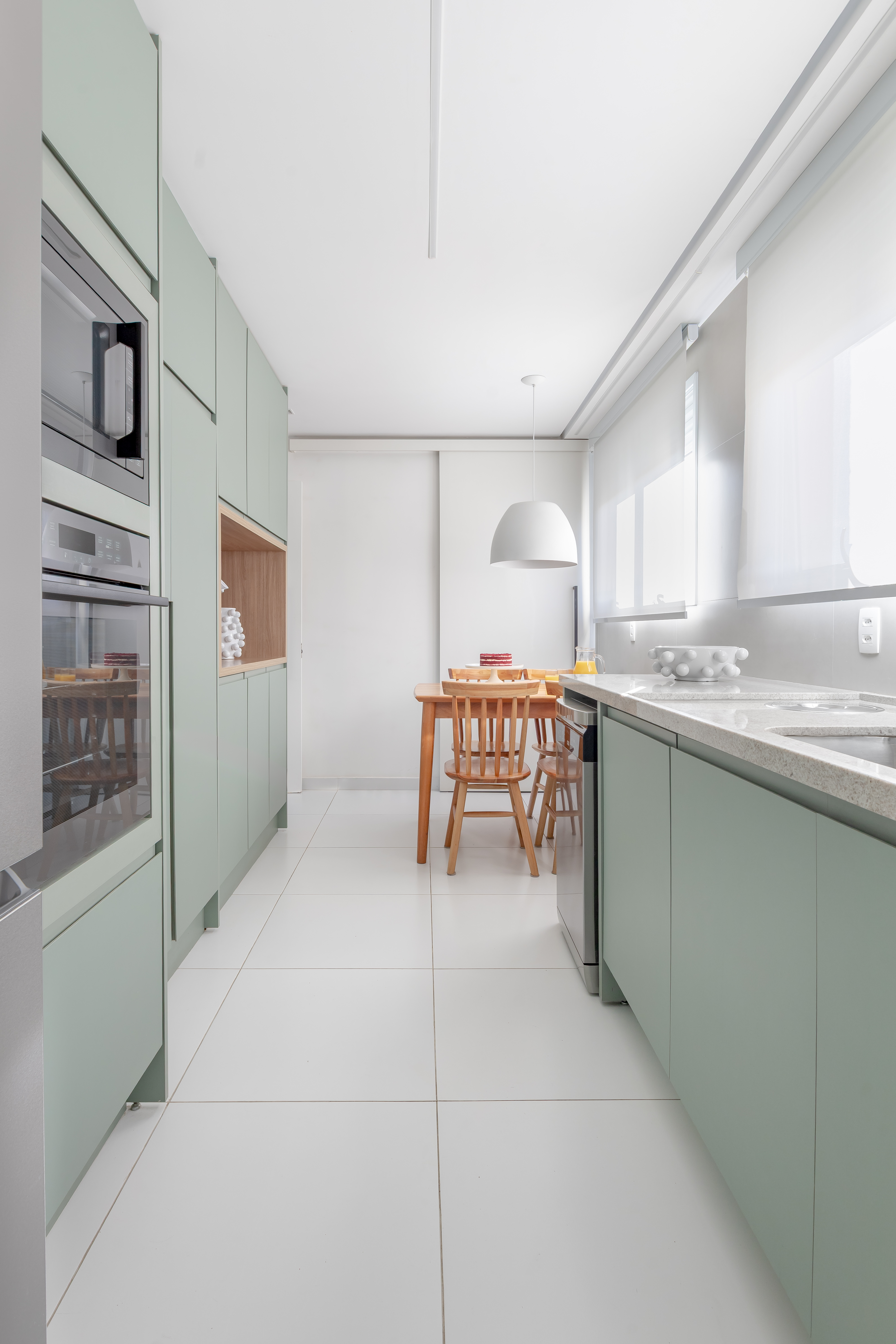 Reforma de apê usa piso e marcenaria originais para destacar revestimentos e pontos de cor. Projeto de Raquel Neves. Cozinha com marcenaria verde.