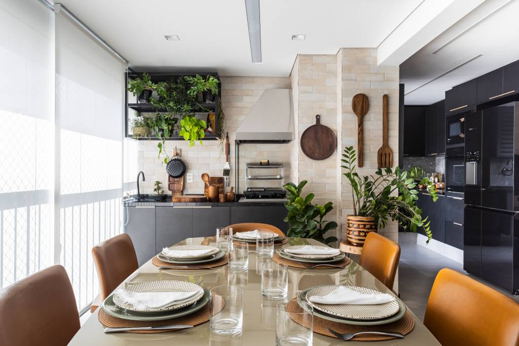 Biofilia e elegância: apartamento tem cozinha preta e muitas plantas na varanda