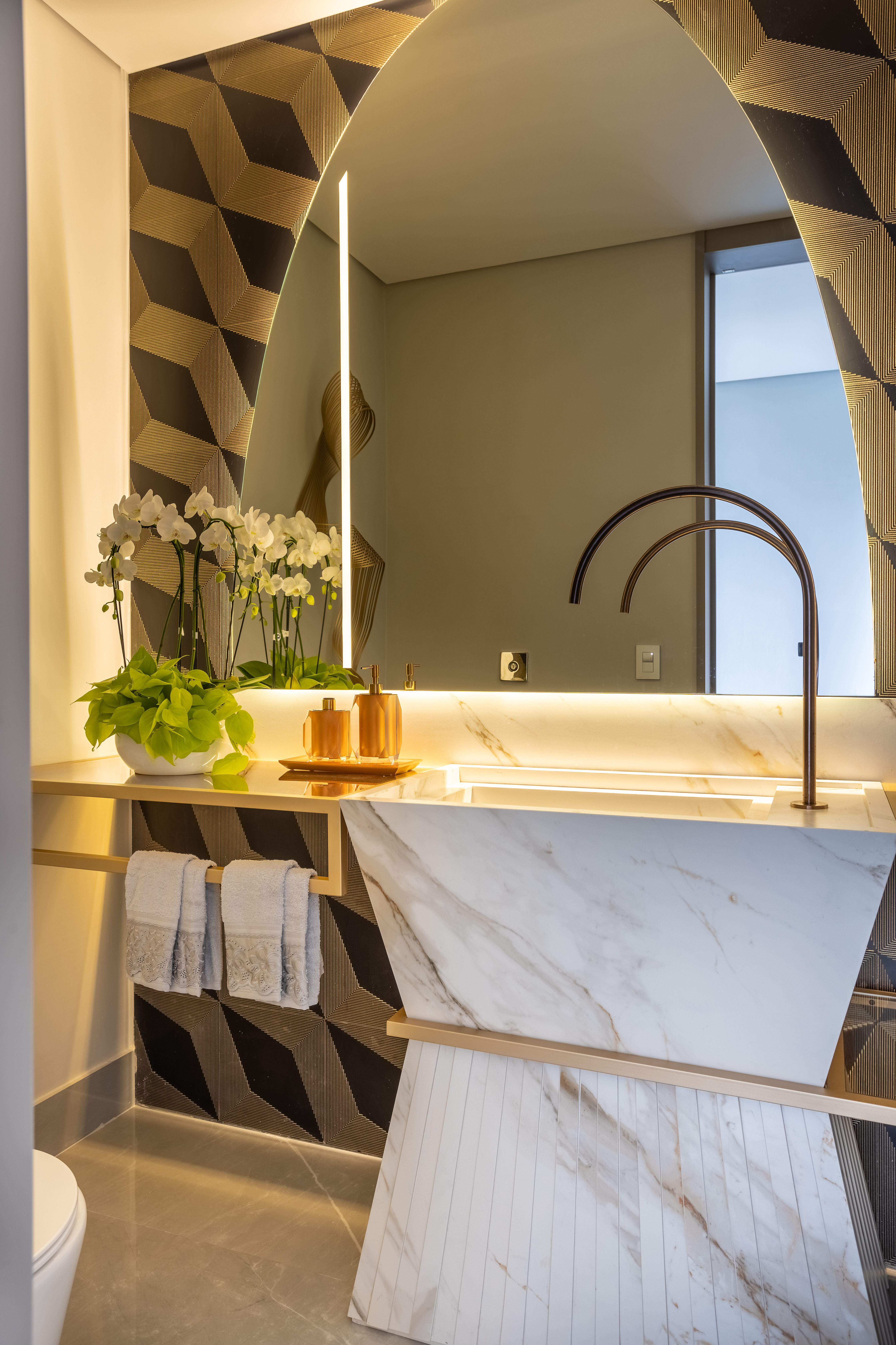 Casa na Granja Viana tem escada de porcelanato plissada, cabeceira de pedra e cristaleira divisória. Projeto de Meneghisso & Pasquotto Arquitetura.