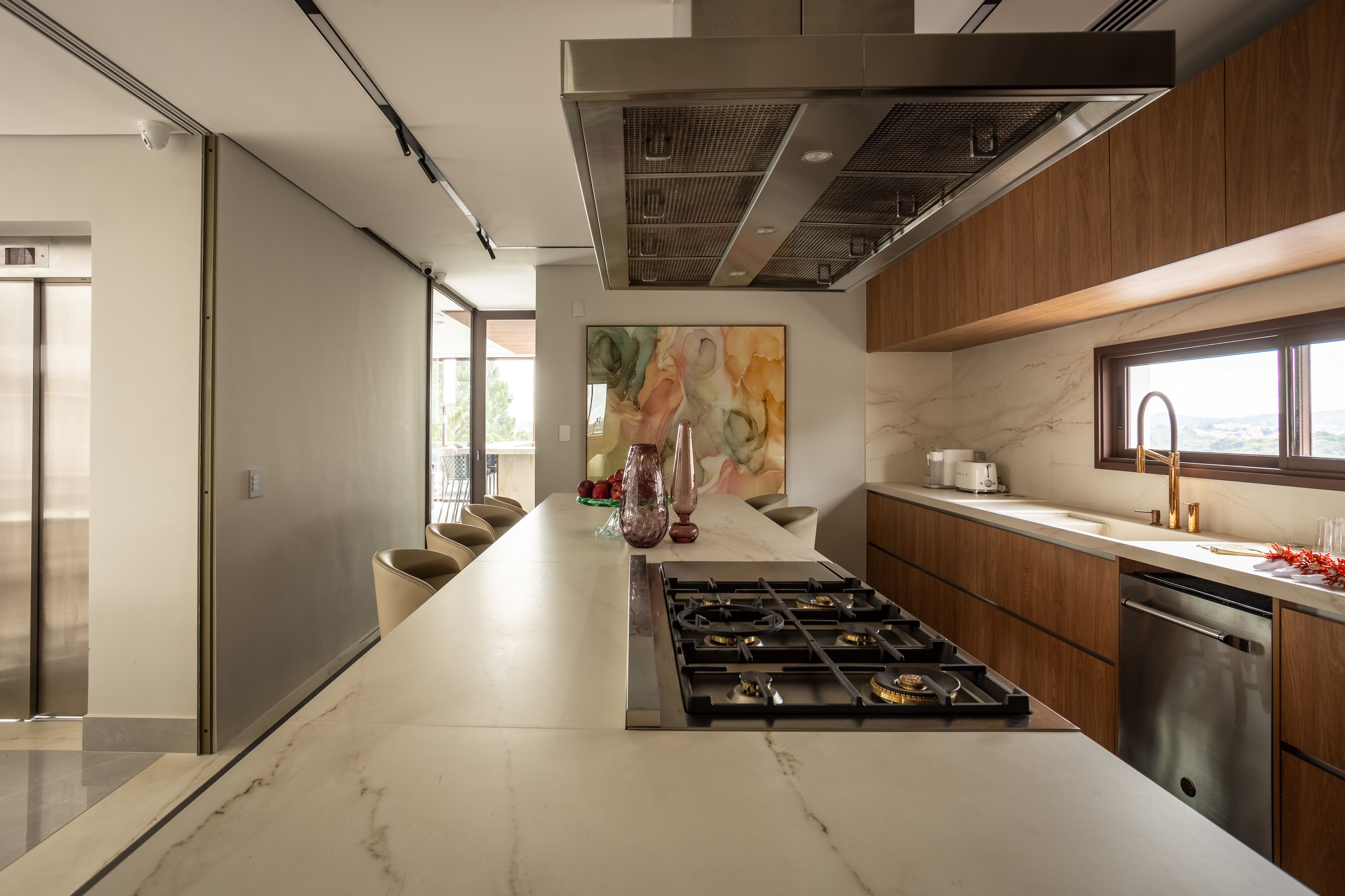 Casa na Granja Viana tem escada de porcelanato plissada, cabeceira de pedra e cristaleira divisória. Projeto de Meneghisso & Pasquotto Arquitetura.