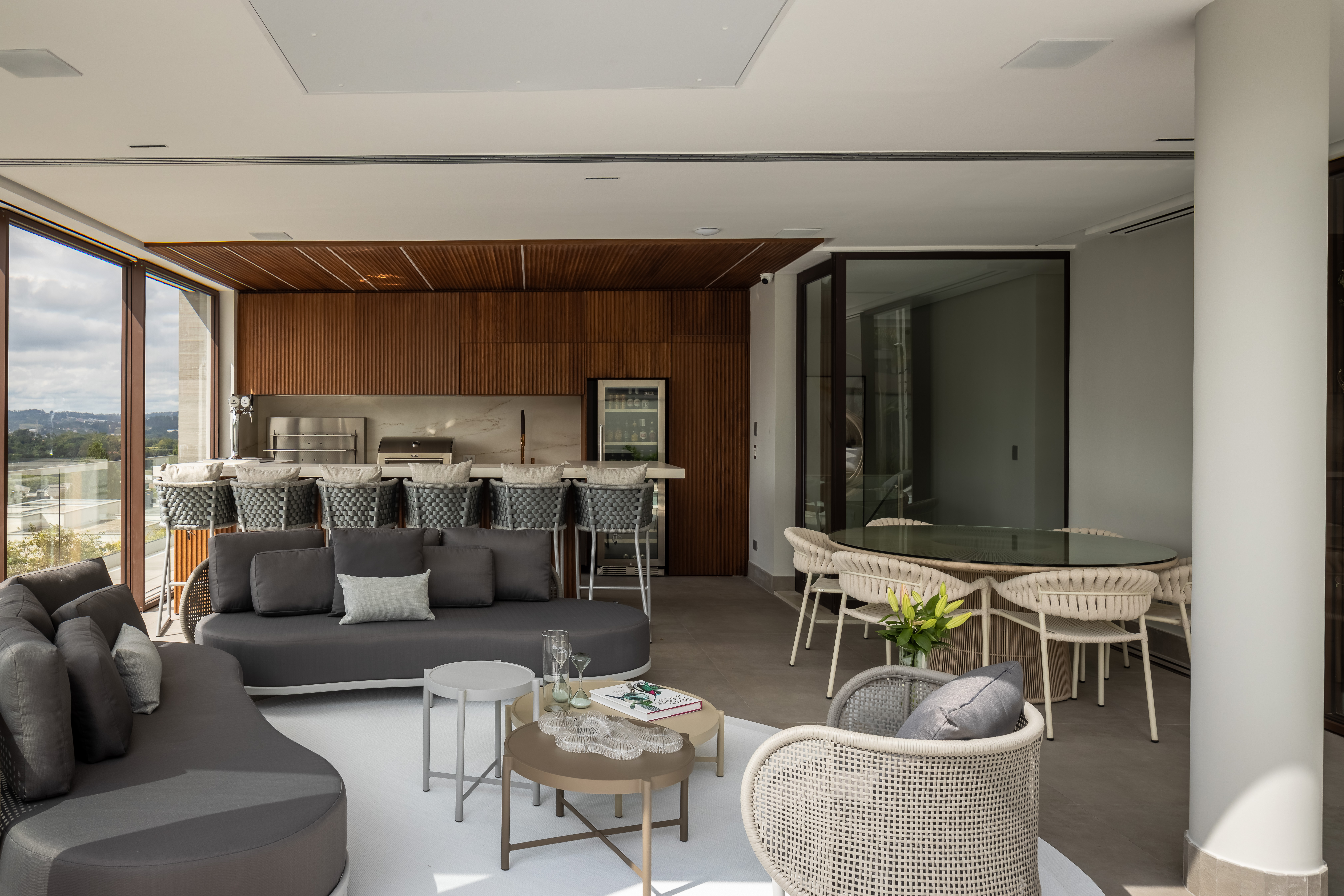 Casa na Granja Viana tem escada de porcelanato plissada, cabeceira de pedra e cristaleira divisória. Projeto de Meneghisso & Pasquotto Arquitetura.